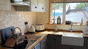 Een moderne keuken met houten aanrechtbladen, een inbouwoven, een raam met uitzicht en een hanglamp.