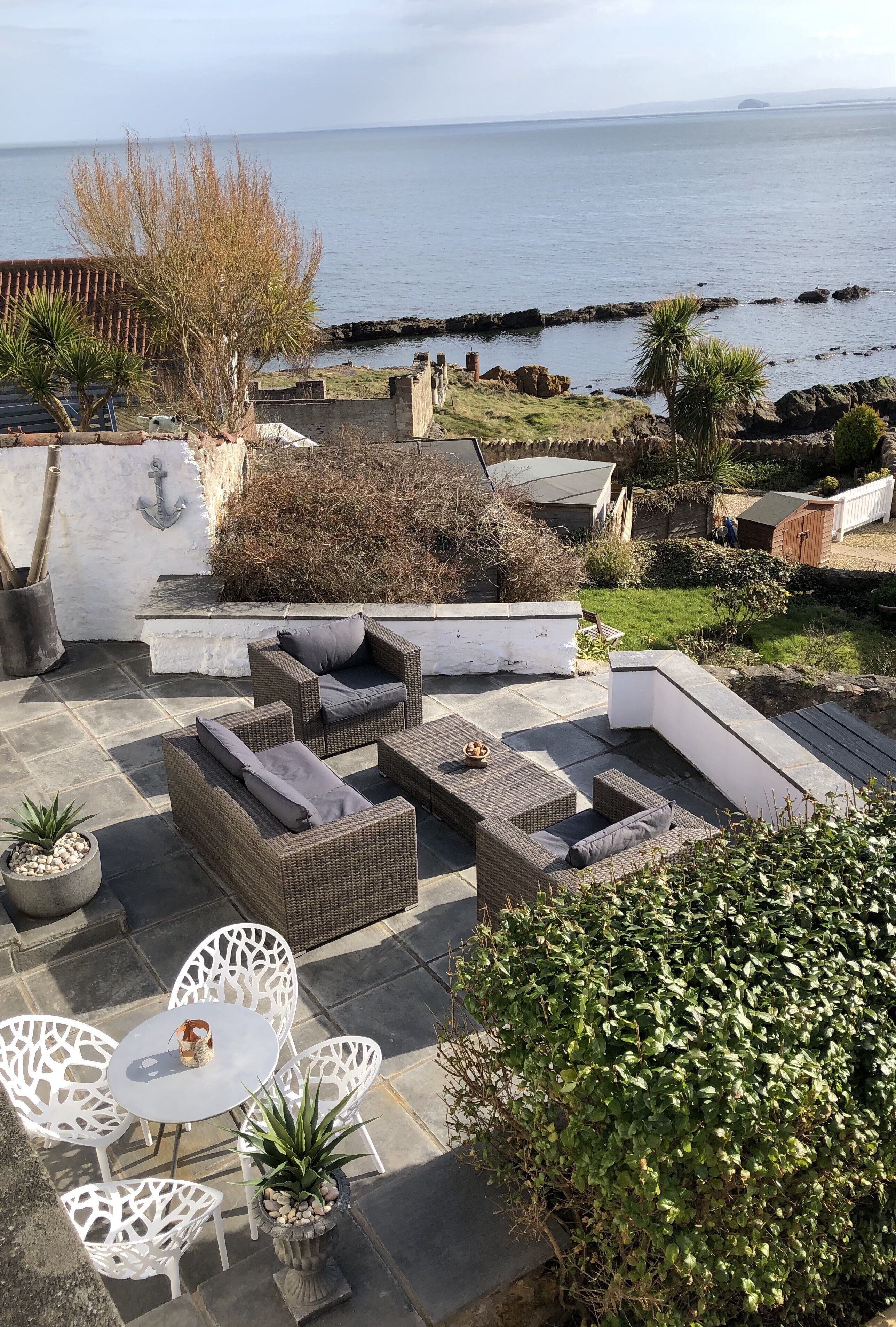 A patio with wicker furniture, white chairs, and a table.
