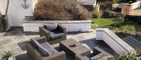 A patio with wicker furniture, white chairs, and a table.