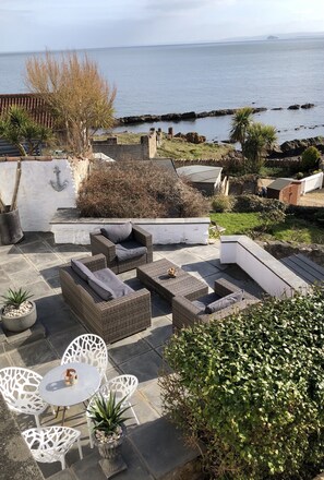 A patio with wicker furniture, white chairs, and a table. - An Idyllic cottage in St.Monans with sea views. (St Monans)