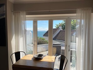 A room with a table and chairs, a view of the sea, and a building with a tiled roof. - An Idyllic cottage in St.Monans with sea views. (St Monans)