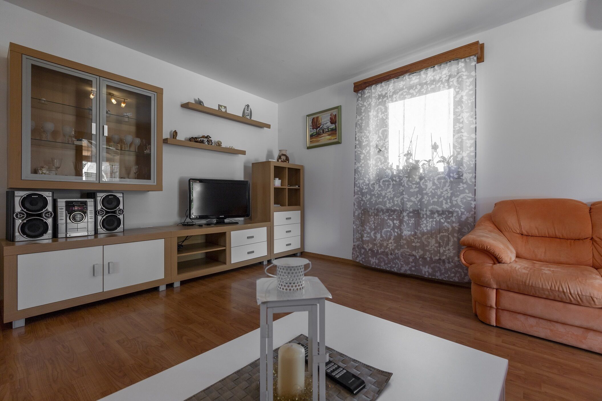 Een woonkamer met een televisie, speakers en een bank.