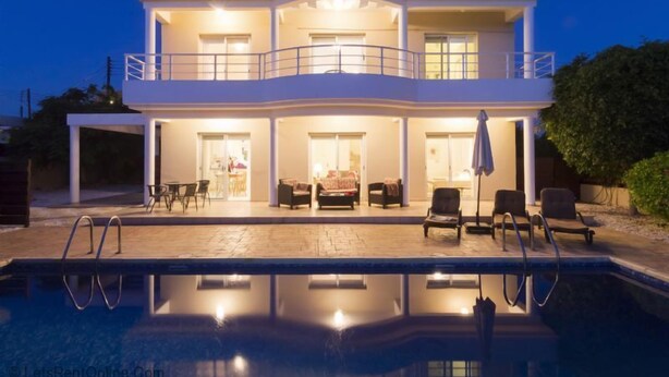 Une maison moderne à deux étages, dotée d’une piscine, d’un espace salon extérieur et d’un balcon.