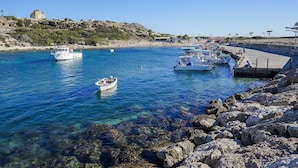 Un port de plaisance avec des bateaux amarrés, une côte rocheuse et un bâtiment situé sur une colline.