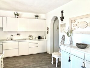 Une cuisine moderne avec des meubles blancs, un plan de travail en bois et un tabouret.