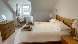 A bedroom with a large bed, wooden headboard, bedside tables, a chair, and a window with curtains. - Unique property, in a peaceful and serene location,  within easy reach of all amenities. (Humbie)