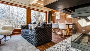 Een moderne woonkamer met een groot raam, een open haard en een eethoek.