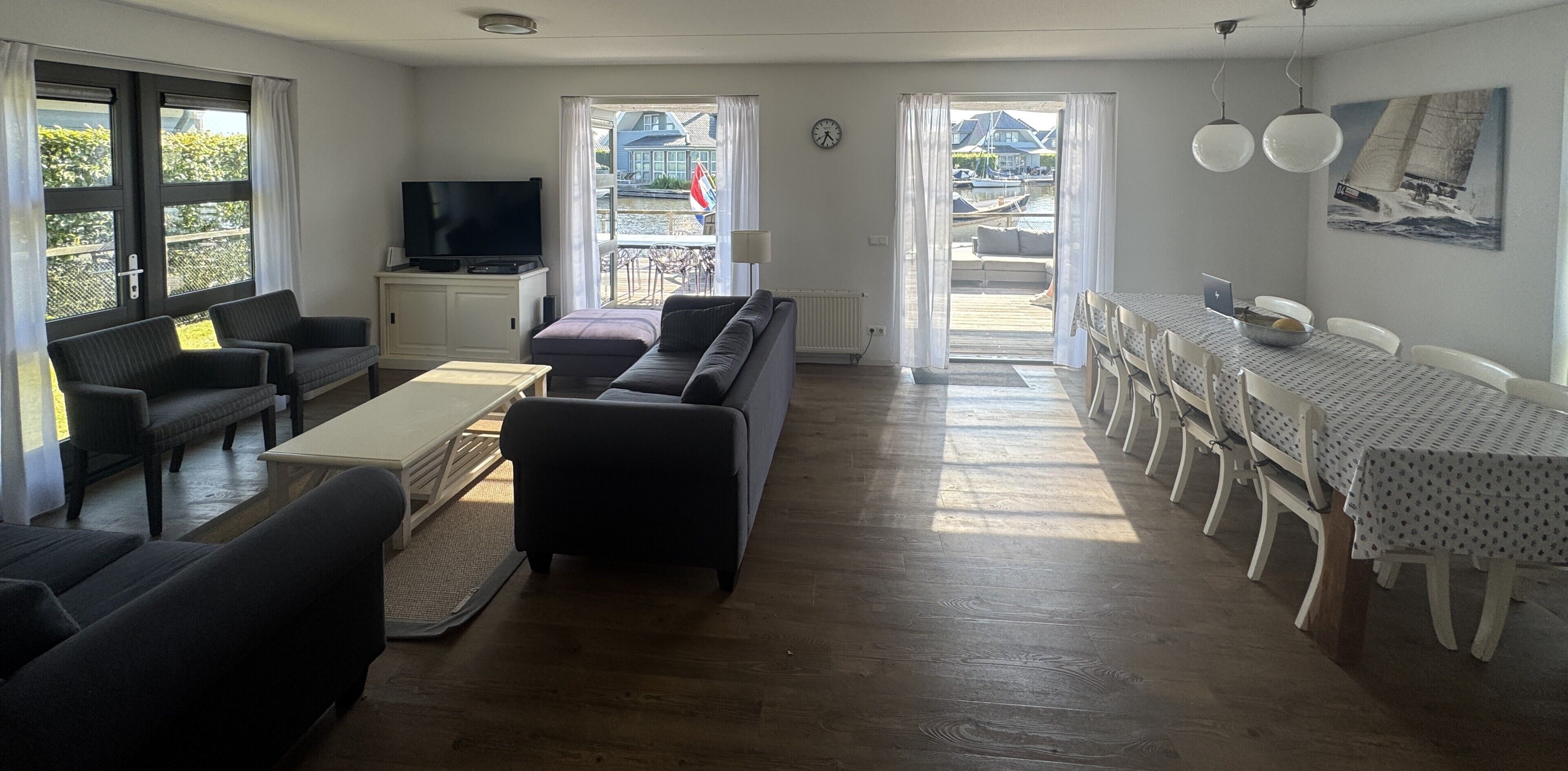 A living room with a sofa, a coffee table, and a TV. There is a dining area with a table and chairs.