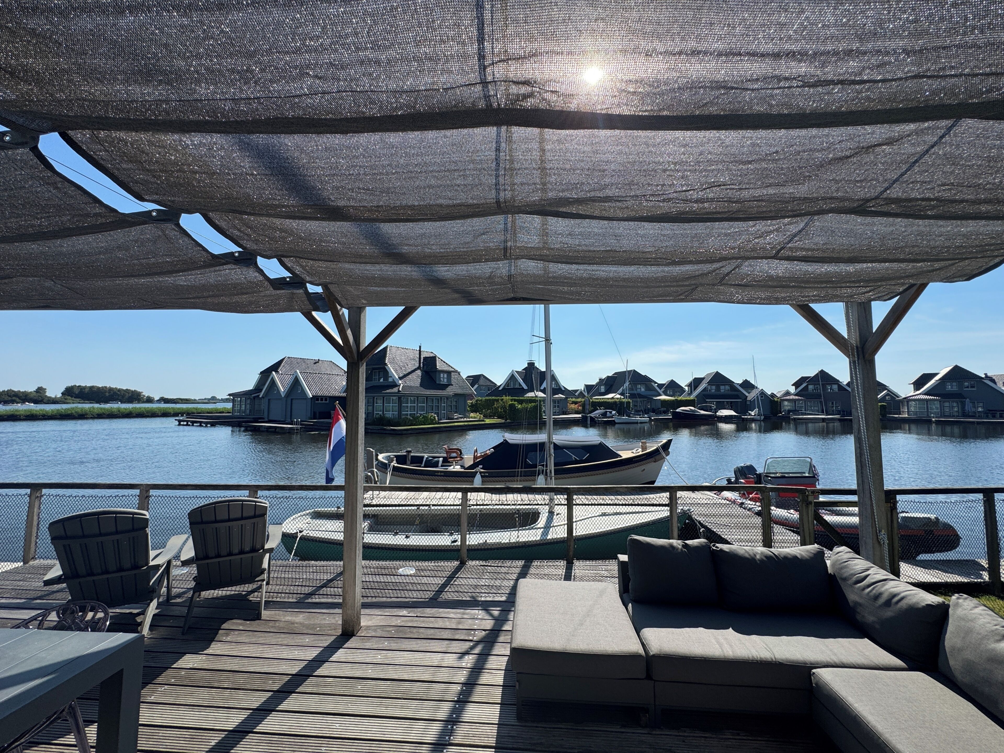 A covered outdoor seating area with a view of a marina and houses across the water.