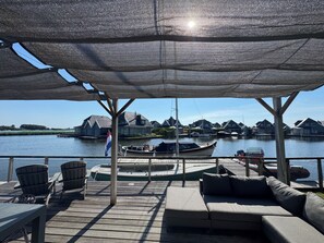 A covered outdoor seating area with a view of a marina and houses across the water.