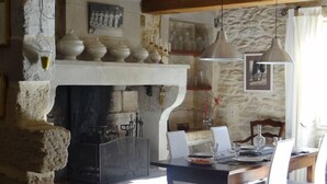 Un coin repas rustique avec une cheminée en pierre, des poutres en bois et une table dressée pour deux personnes.