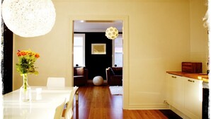 A kitchen with wooden cabinets, a white countertop, and a dining area with a table and chairs. - Exceptional Luxury Apartment In 101 Reykjavik, The Centre Of Town
 (Reykjavik)
