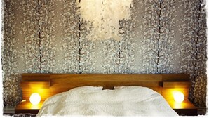 A bedroom with a wooden headboard, a white bedspread, and a wall with a tree pattern. - Exceptional Luxury Apartment In 101 Reykjavik, The Centre Of Town
 (Reykjavik)
