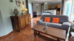 Un salon spacieux avec un canapé, une table basse en bois et une cuisine à l’arrière-plan.