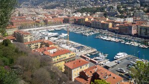 Un port de plaisance où de nombreux bateaux sont amarrés, entouré de bâtiments aux toits recouverts de tuiles rouges.