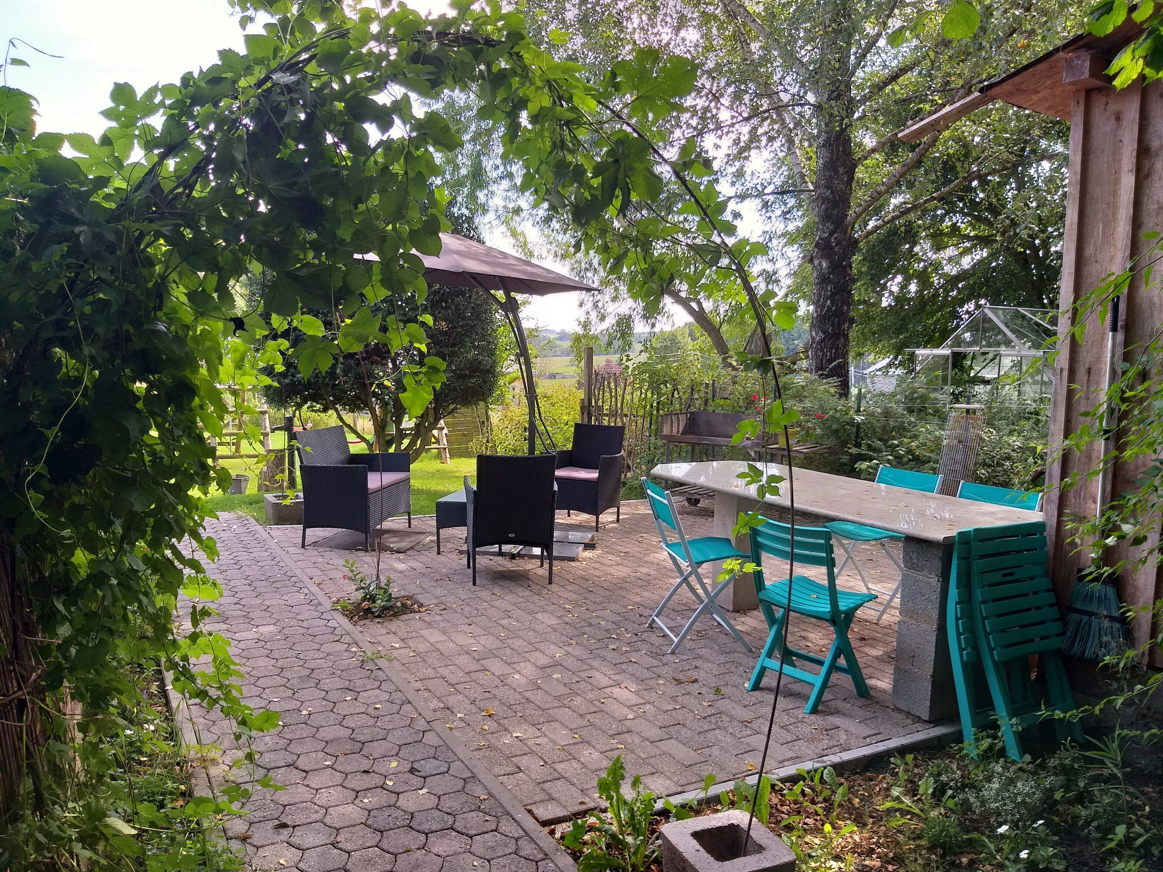 Un espace patio doté d’un revêtement de sol hexagonal, de mobilier d’extérieur et d’une pergola offrant de l’ombre.
