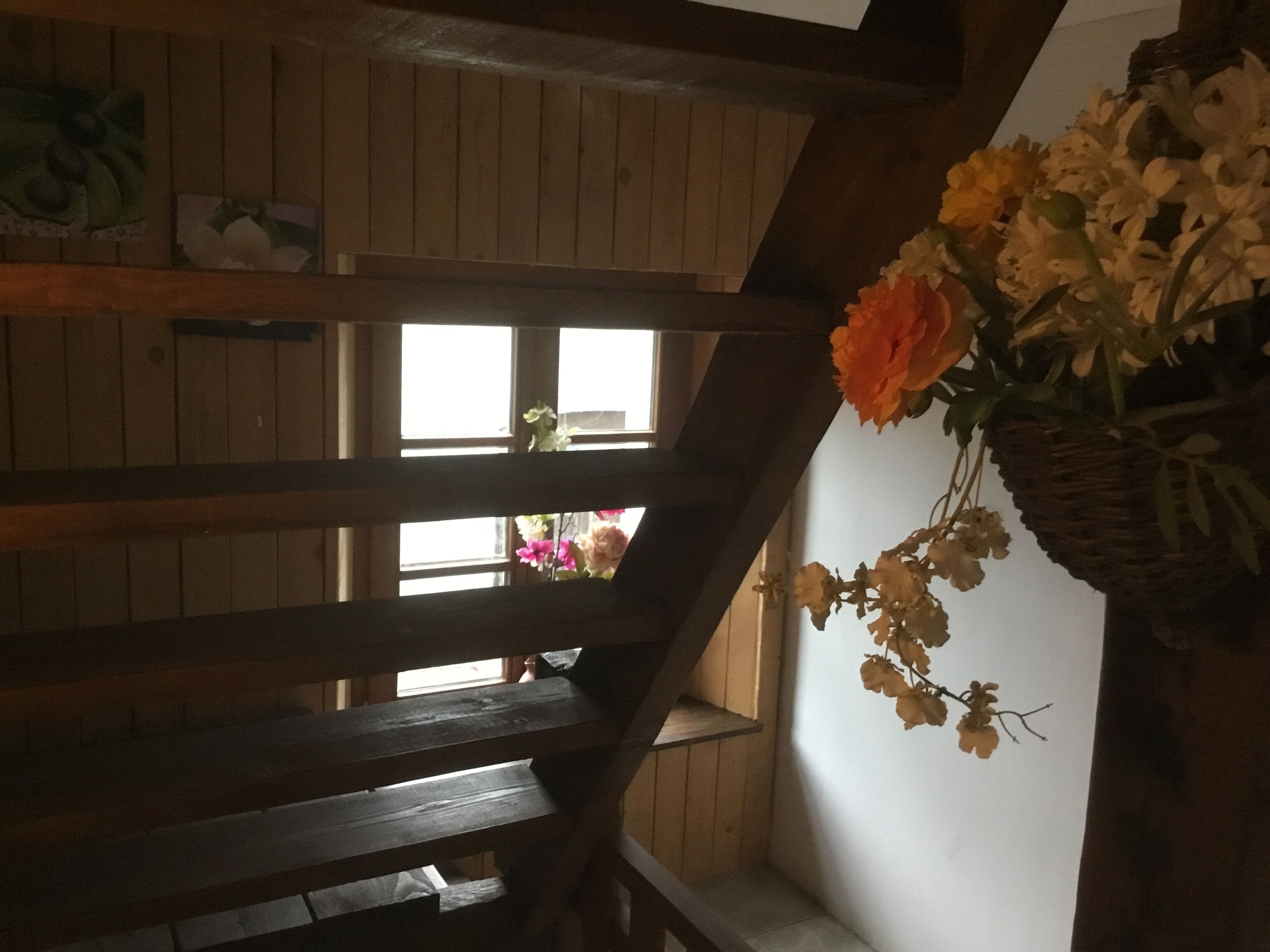Eine Holztreppe mit einem Blumenkorb auf der rechten Seite.