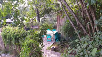 A garden area with a table and chairs, surrounded by dense foliage and trees.