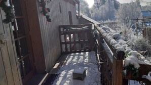 Un edificio de madera con balcón, nieve en el suelo y valla de madera.