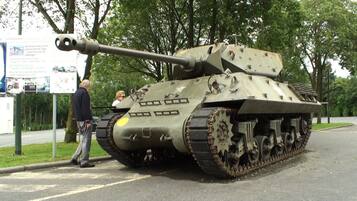 A military tank on display with a signboard in the background.