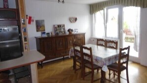 Un comedor con una mesa y sillas de madera, un refrigerador y un armario con varios objetos encima.