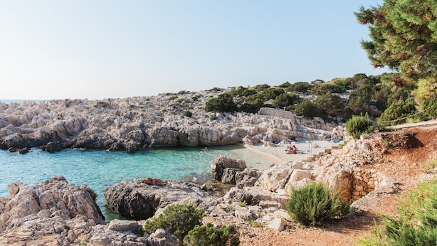 A rocky coastal area with clear blue water, a sandy beach, and a stone wall. - Villa With Private Pool (Magganos)