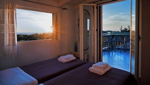 A room with two beds, a window with curtains, a shower area, and a balcony with chairs. - Villa With Private Pool (Magganos)