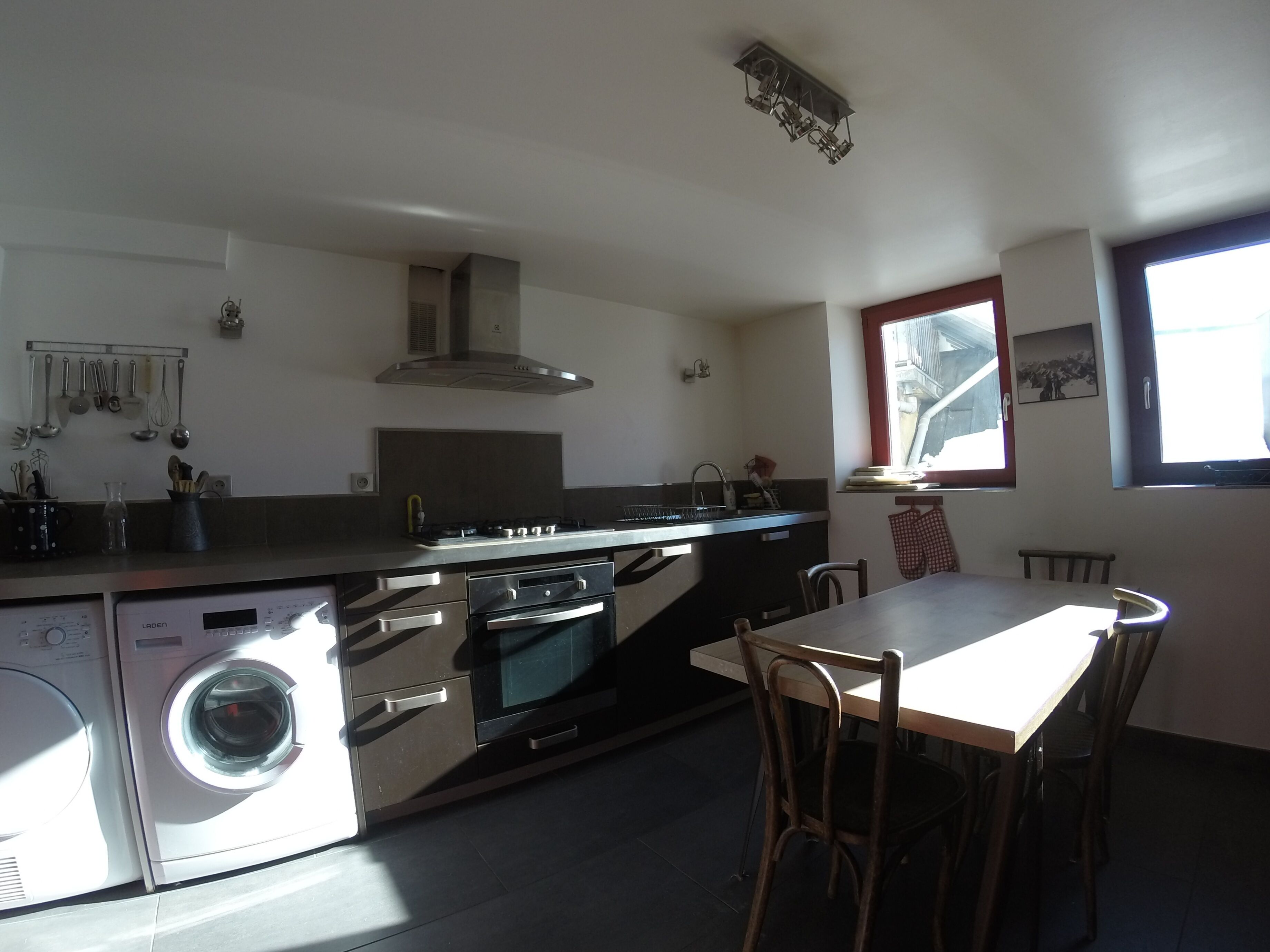 A compact kitchen with a built-in washer and dryer, a stove, and a dining area with a table and chairs.