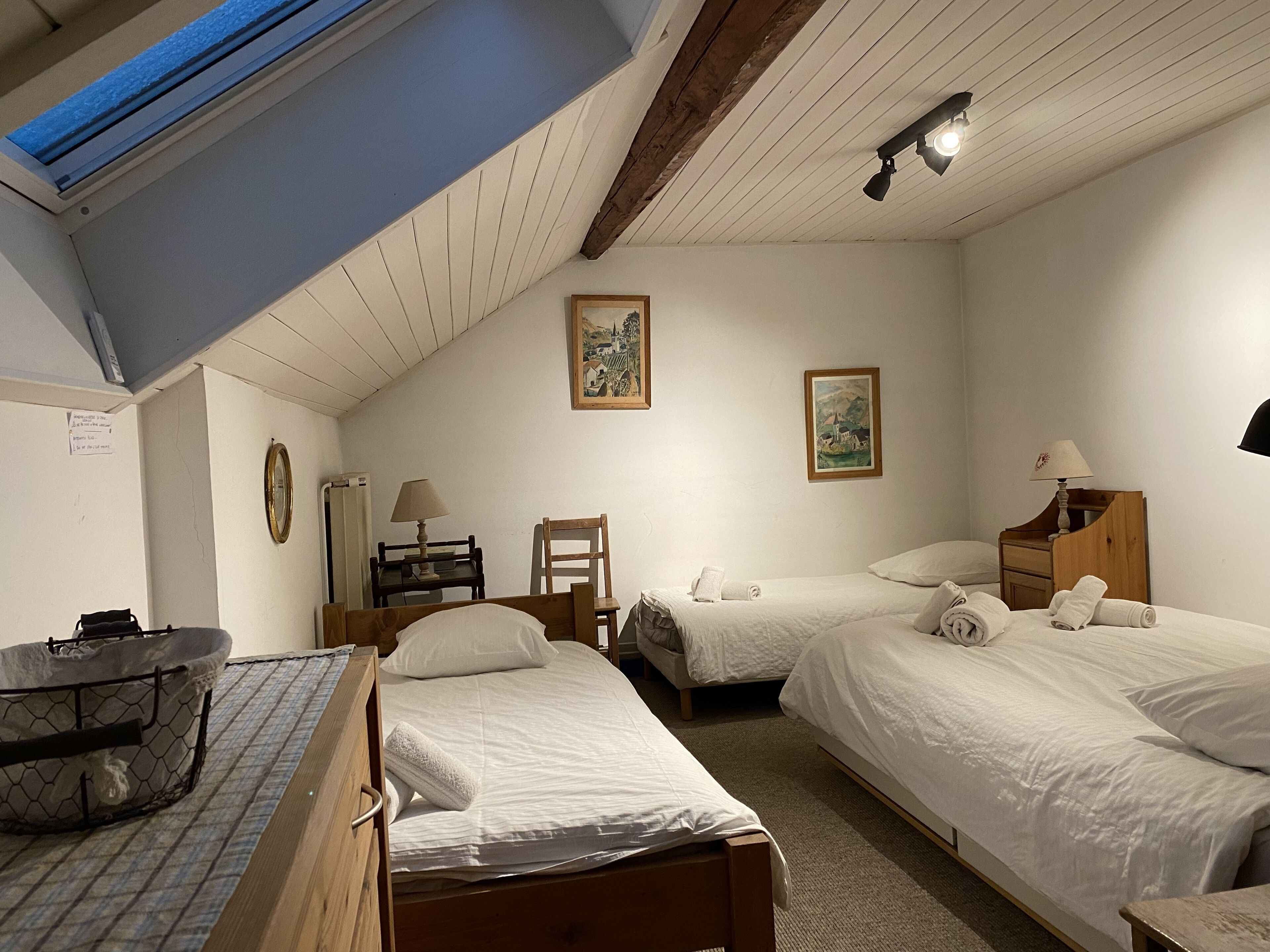 A cozy bedroom with two beds, a desk, a chair, and a small table.