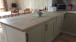 A kitchen with a wooden countertop, a microwave, and a bowl on a mat. - Spacious property in rural setting
Free Wifi (callington)