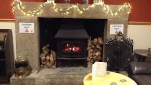 A fireplace with a caution sign, logs, and a table with coaster badges. - Spacious property in rural setting
Free Wifi (callington)