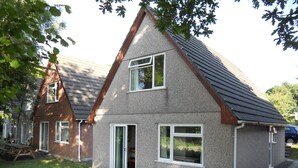 A two-story house with a sloped roof, a wooden picnic table in the front yard, and a car parked nearby. - Spacious property in rural setting
Free Wifi (callington)