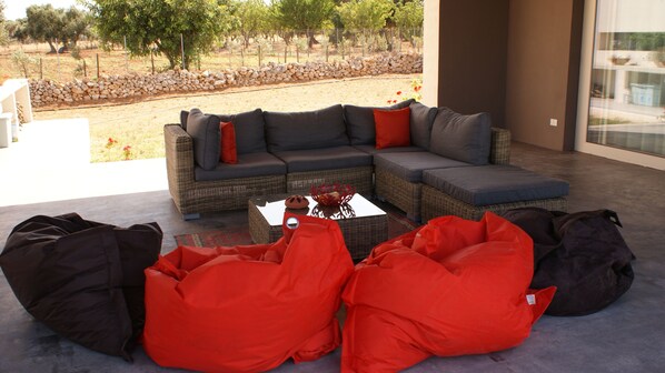 A modern outdoor seating area with a sectional sofa, red bean bags, and a coffee table. - Modern Villa, spectacular private pool with sea view, only 3 minutes to beach! (Serranova)