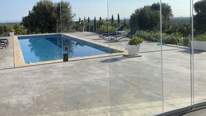 En tydlig vy över en swimmingpool med utsikt över det omgivande landskapet, inklusive träd och en avlägsen horisont.