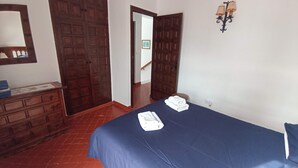 Una habitación con una cama, un aparador y dos puertas que dan a otras áreas.