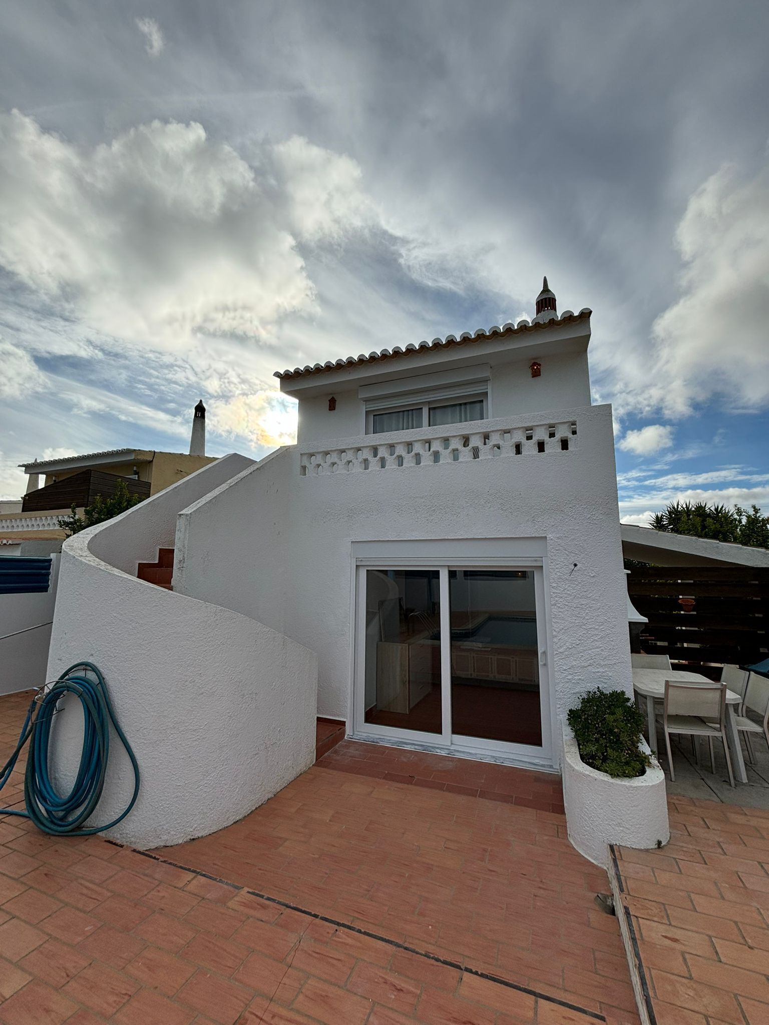 A white building with a tiled roof, a chimney, and a large sliding glass door.