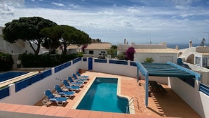 A rooftop pool area with blue lounge chairs, a swimming pool, and a view of the cityscape under a partly cloudy sky. - 2-bed Villa with Private Pool and Panoramic Views in a quiet residential area (Lagos)