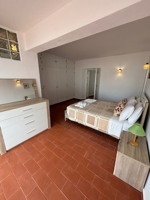 Une chambre à coucher comprenant un lit, une commode, une armoire et un miroir.