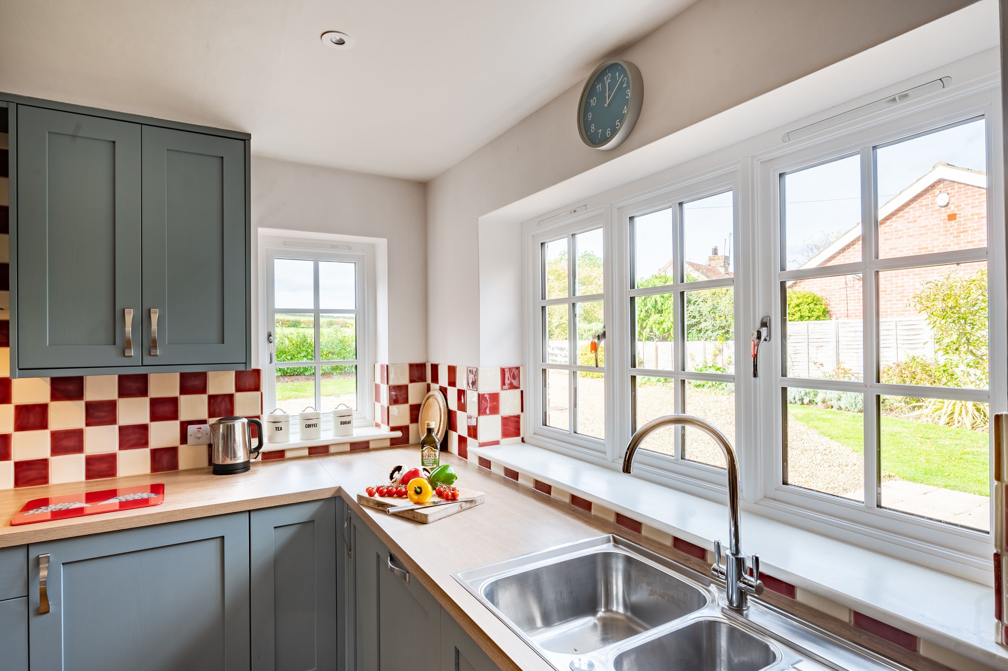 A kitchen with a large window, a sink, and a clock on the wall.