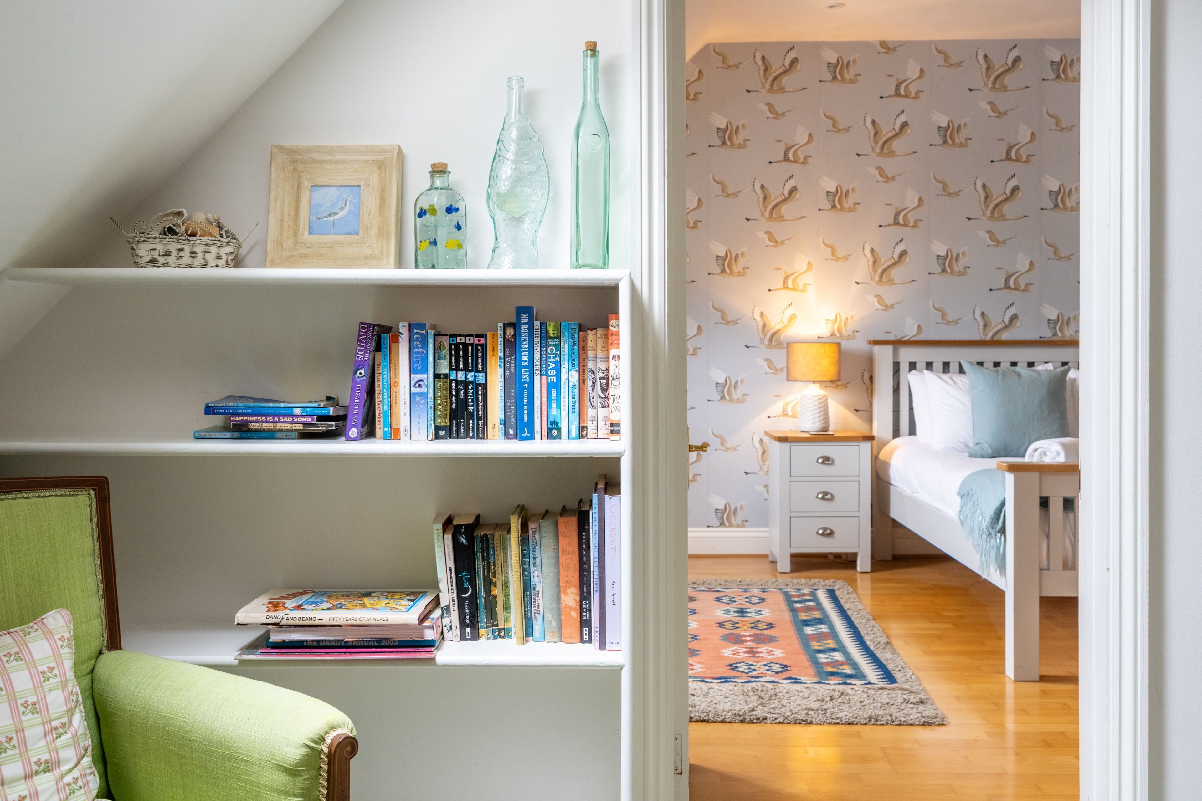 A cozy bedroom with a bed, nightstand, and a bookshelf filled with books.