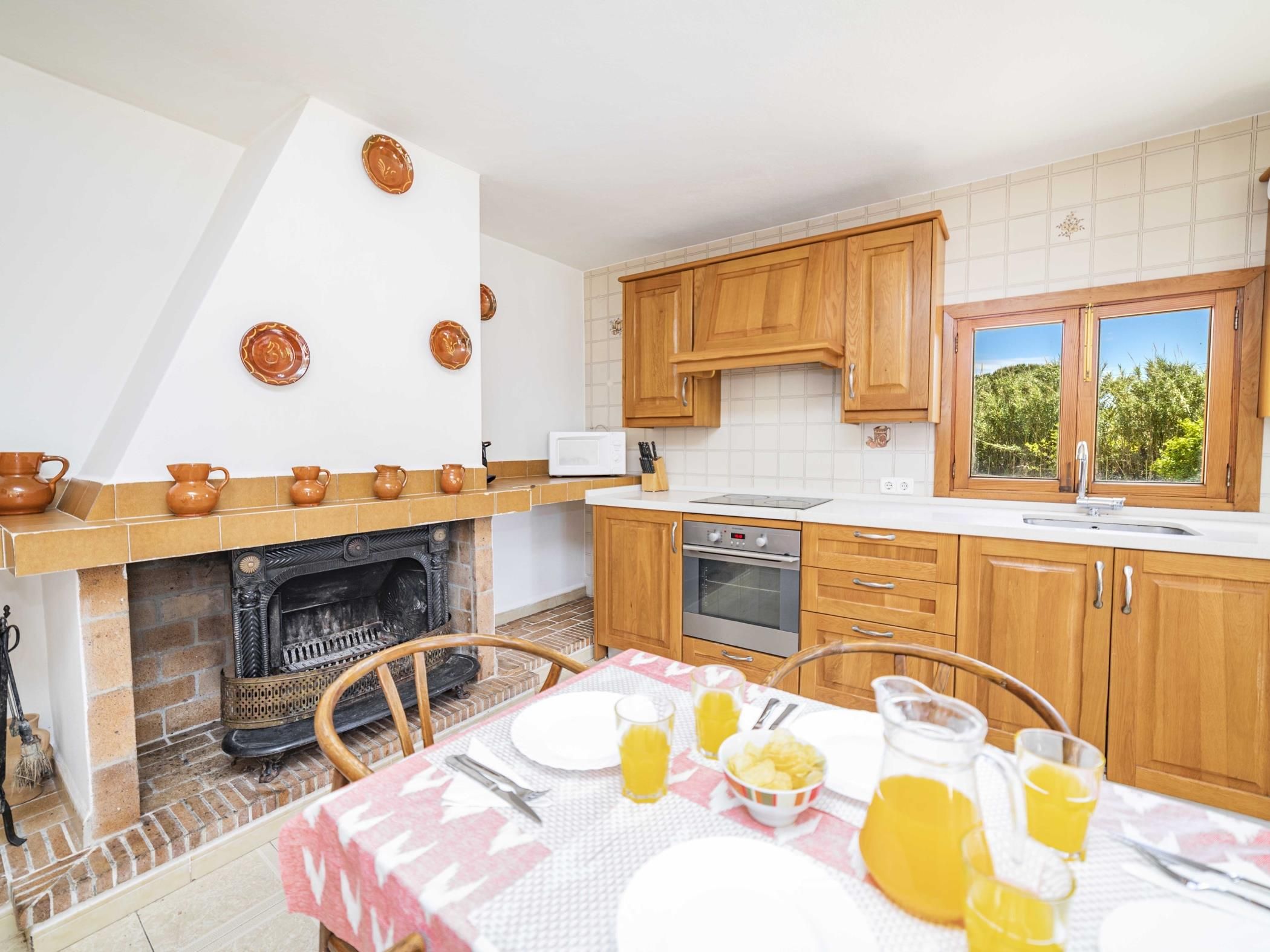 A kitchen with wooden cabinets, a microwave, an oven, and a dining area with a table set for breakfast.