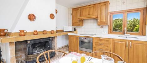 Une cuisine dotée de meubles en bois, d’un four à micro-ondes, d’un four traditionnel et d’un coin repas avec une table mise pour le petit-déjeuner.