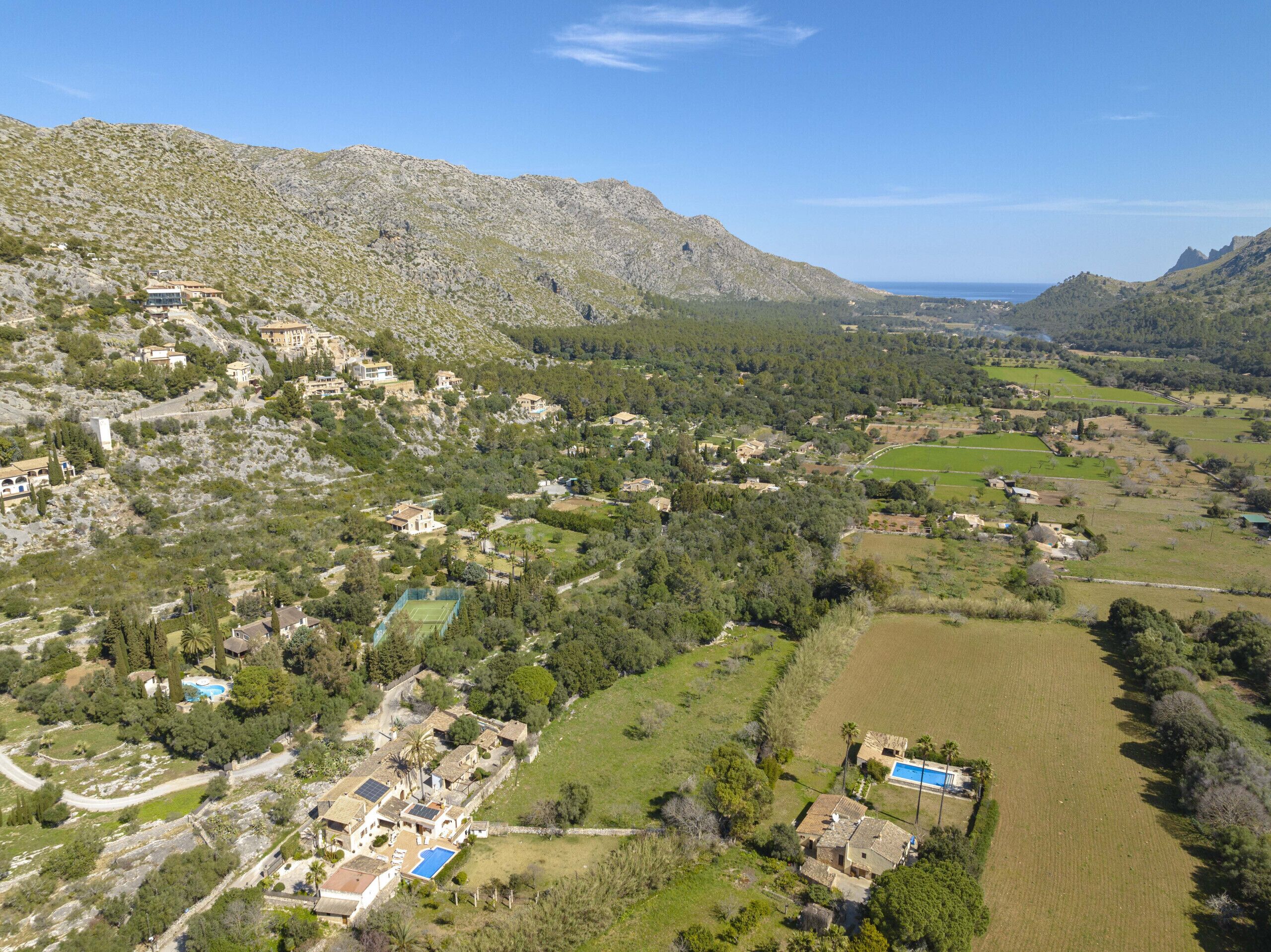 A mountainous landscape with scattered houses and a clear view of the sea.
