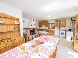 Une cuisine avec des meubles de rangement en bois, une table à manger dressée pour le petit-déjeuner et un lave-linge.