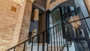 A staircase with a wrought iron railing, brick walls, and a large window with a view of the interior. - Apartment with maritime essence in an unbeatable location (Barcelona)