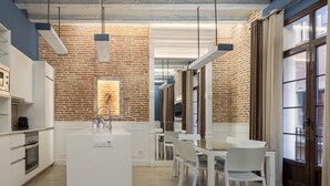 A modern kitchen with a brick wall, white cabinetry, and pendant lighting. - Apartment with maritime essence in an unbeatable location (Barcelona)