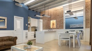 A modern kitchen with white cabinetry, a brick accent wall, and pendant lighting. - Apartment with maritime essence in an unbeatable location (Barcelona)