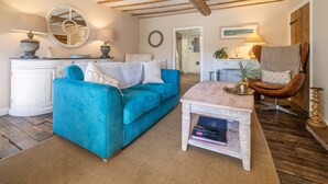 A living room with a blue sofa, a white coffee table, and a wooden ceiling. - Orchard Cottage, Ringstead, Norfolk (Ringstead)