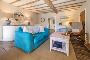 A living room with a blue sofa, a white coffee table, and a wooden ceiling. - Orchard Cottage, Ringstead, Norfolk (Ringstead)