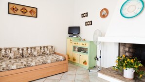 Una sala de estar con sofá, televisión, mueble y chimenea.